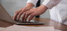 Hands typing report on keyboard